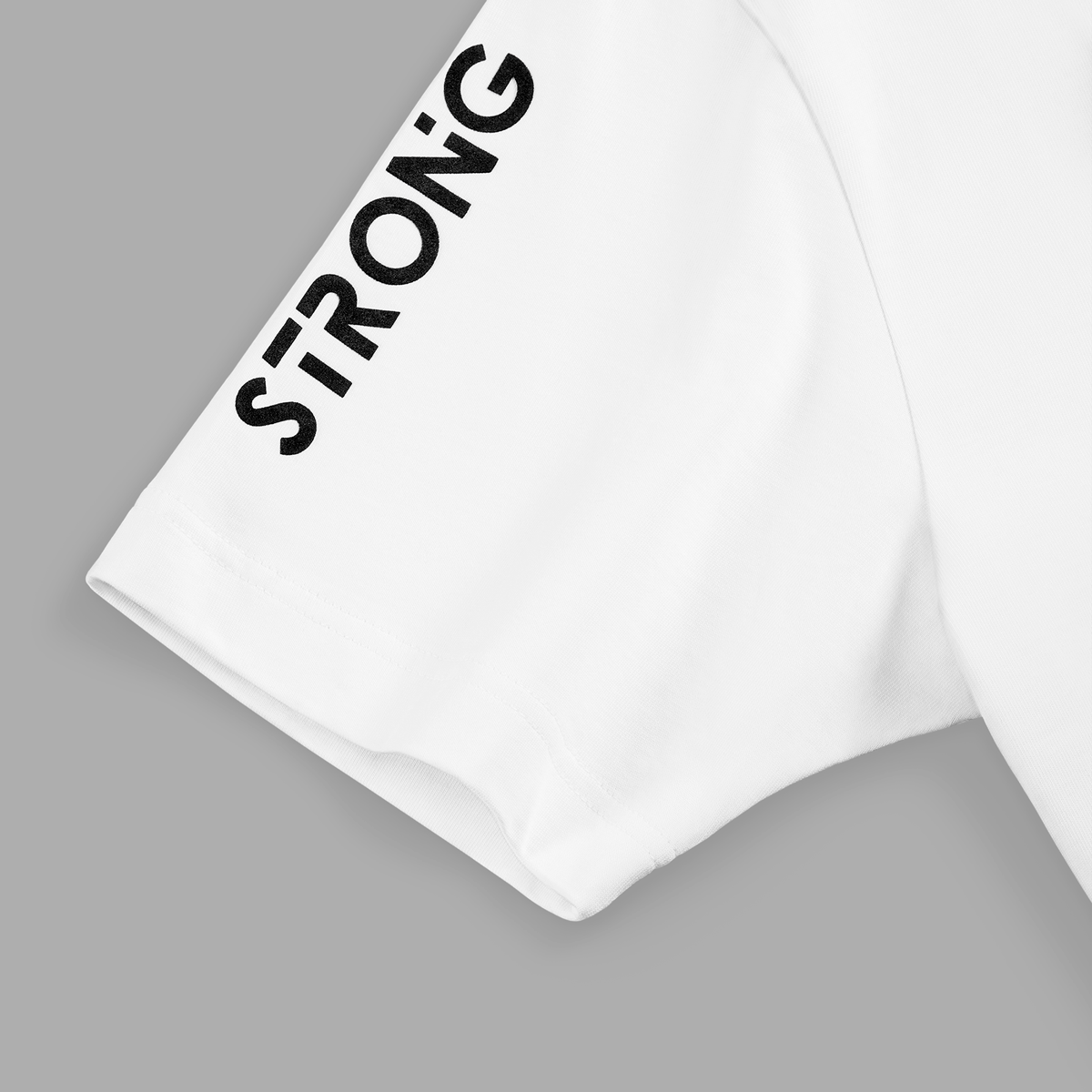 Close-up of right white t-shirt sleeve with bold black STRONG text printed vertically