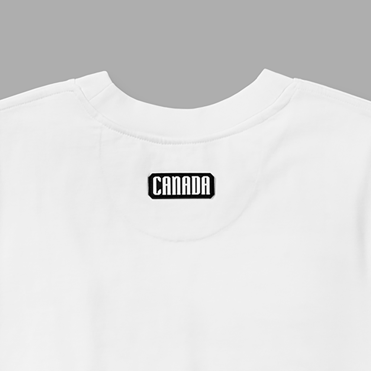 Close-up of black and white Canada patch below back neckline on white t-shirt