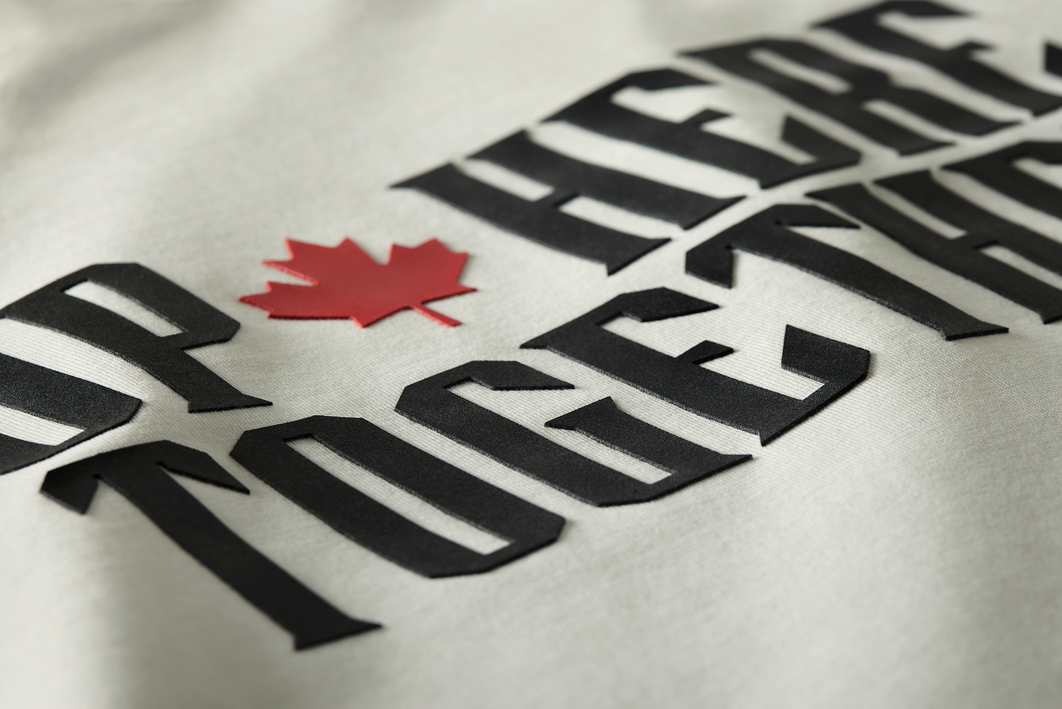 High-density black print with red maple leaf on a white t-shirt - bold, raised lettering that resists fading.