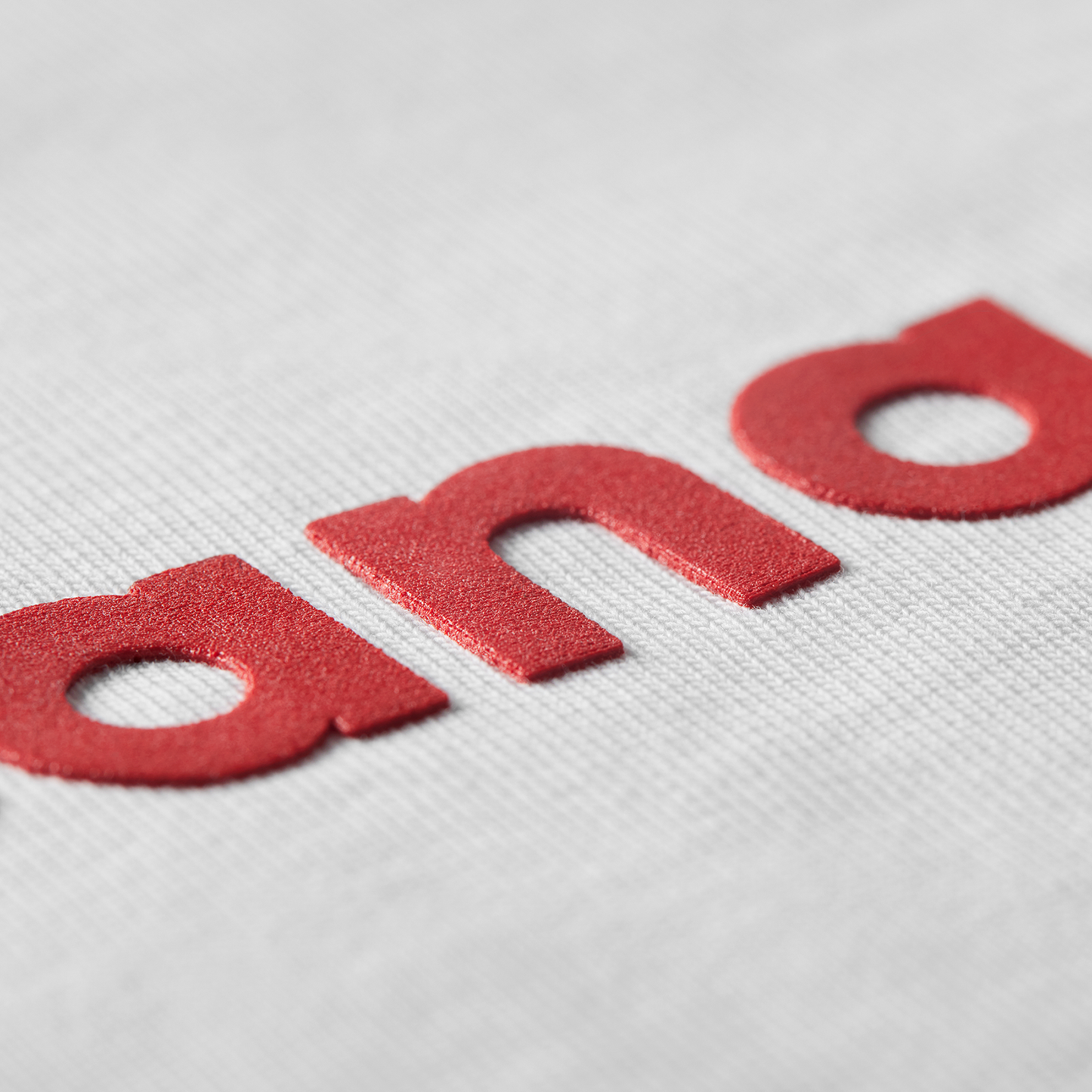 Close-up of red high-density printed letters Proudly Canadian text on white t-shirt