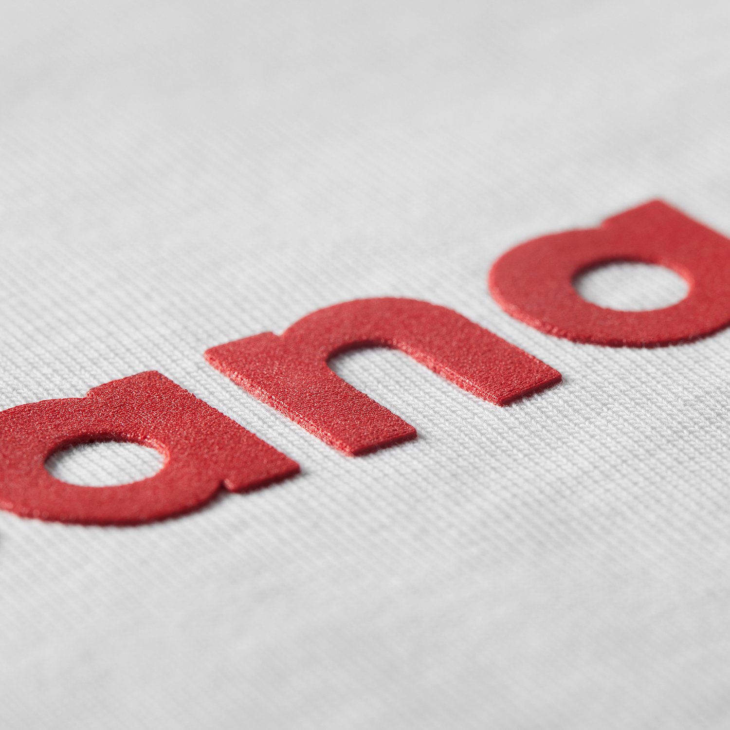 Close-up of red high-density printed letters Proudly Canadian text on white t-shirt