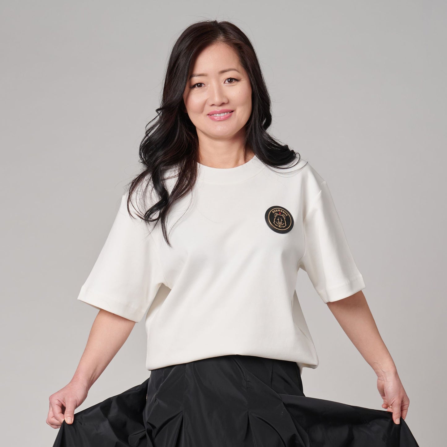Female model wearing Kermodee Spirit Unisex T-Shirt on cream off-white fabric with Kermode bear emblem