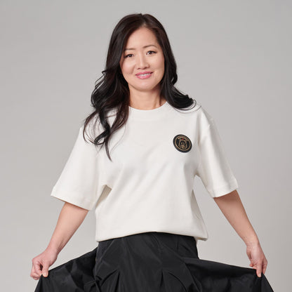 Female model wearing Kermodee Spirit Unisex T-Shirt on cream off-white fabric with Kermode bear emblem