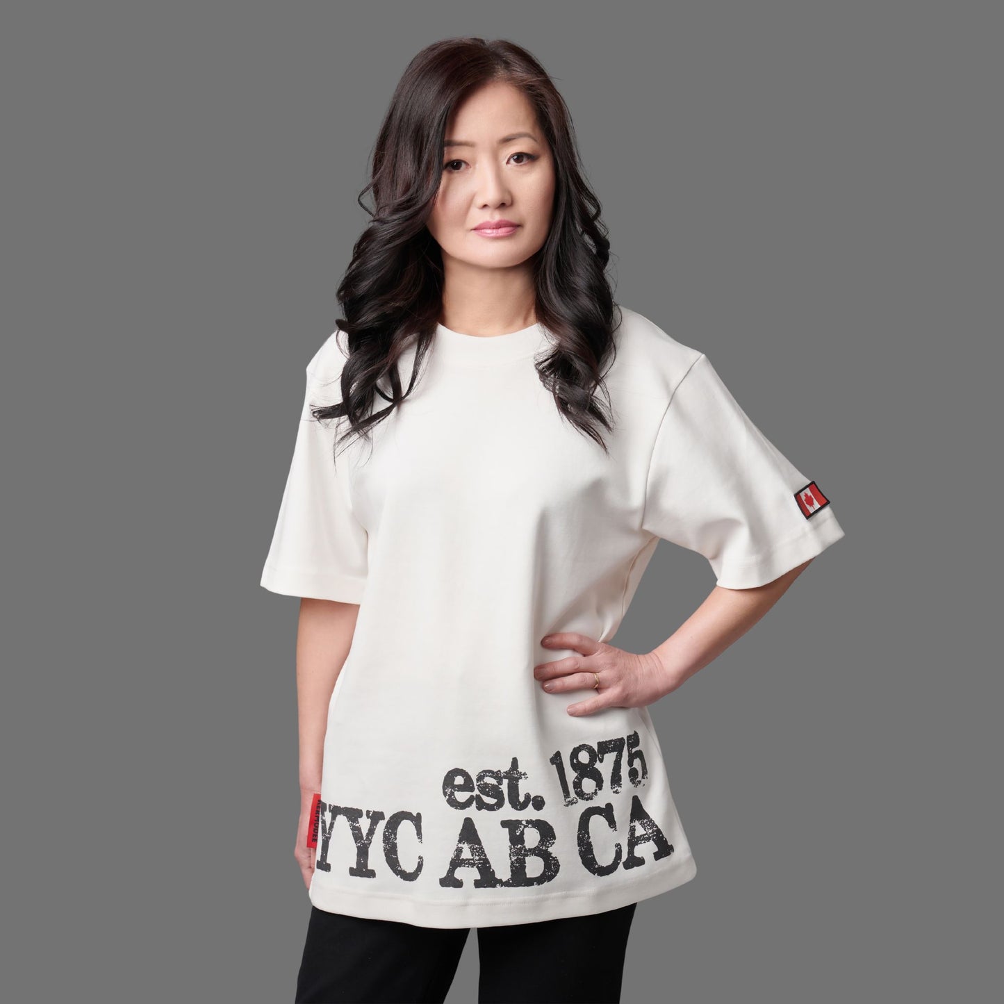 Female model wearing Calgary Alberta Heritage Unisex T-Shirt featuring distressed YYC AB CA EST. 1875 heritage graphic