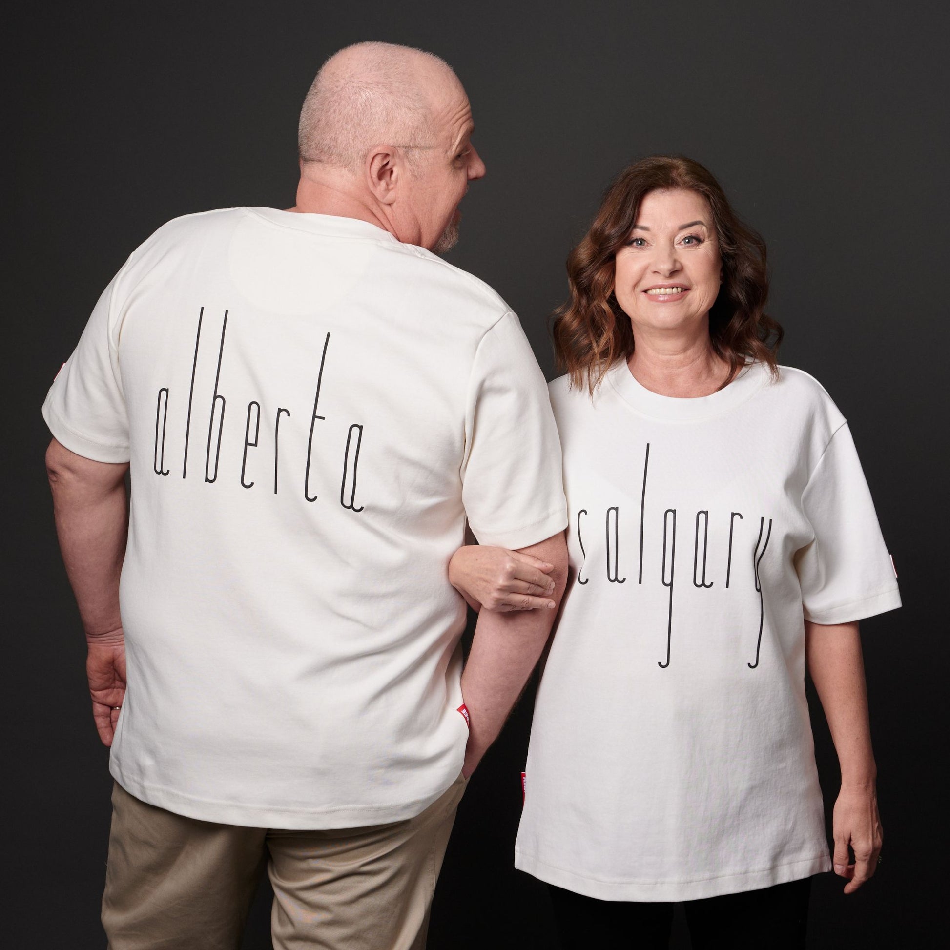Male and female models wearing Calgary Alberta Unisex T-Shirts with Canadian City Pride design and raised Calgary lettering showing front and back views