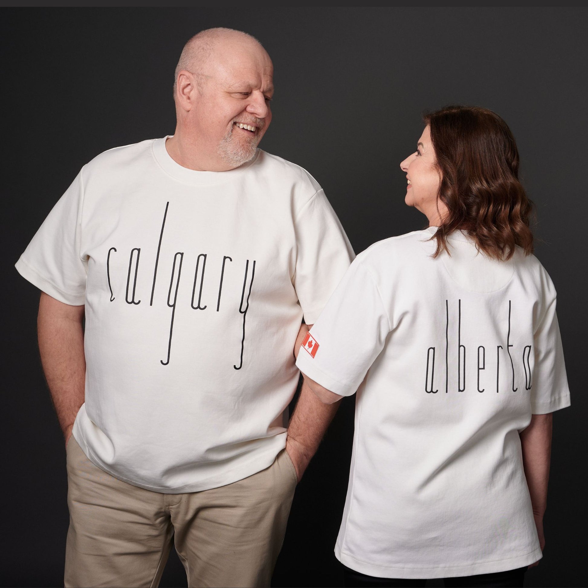 Male and female models wearing Calgary Alberta Unisex T-Shirts with Canadian City Pride design and raised Calgary lettering showing front and back views