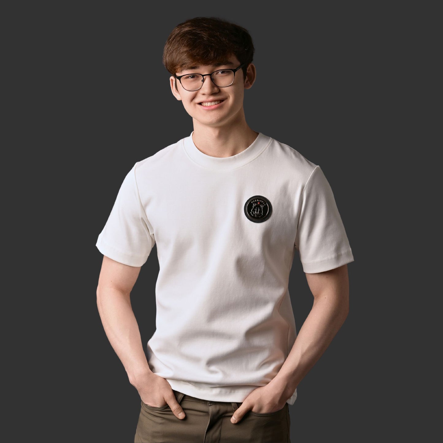 Male model wearing Kermodee Spirit Unisex T-Shirt with gold-outlined Kermode bear emblem on cream off-white fabric