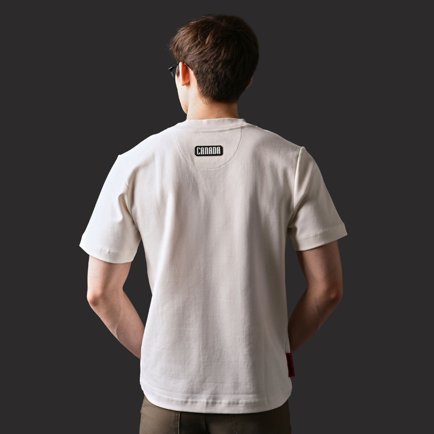 Back view of male model wearing Kermodee Spirit Unisex T-Shirt with black silicone CANADA patch below neckline