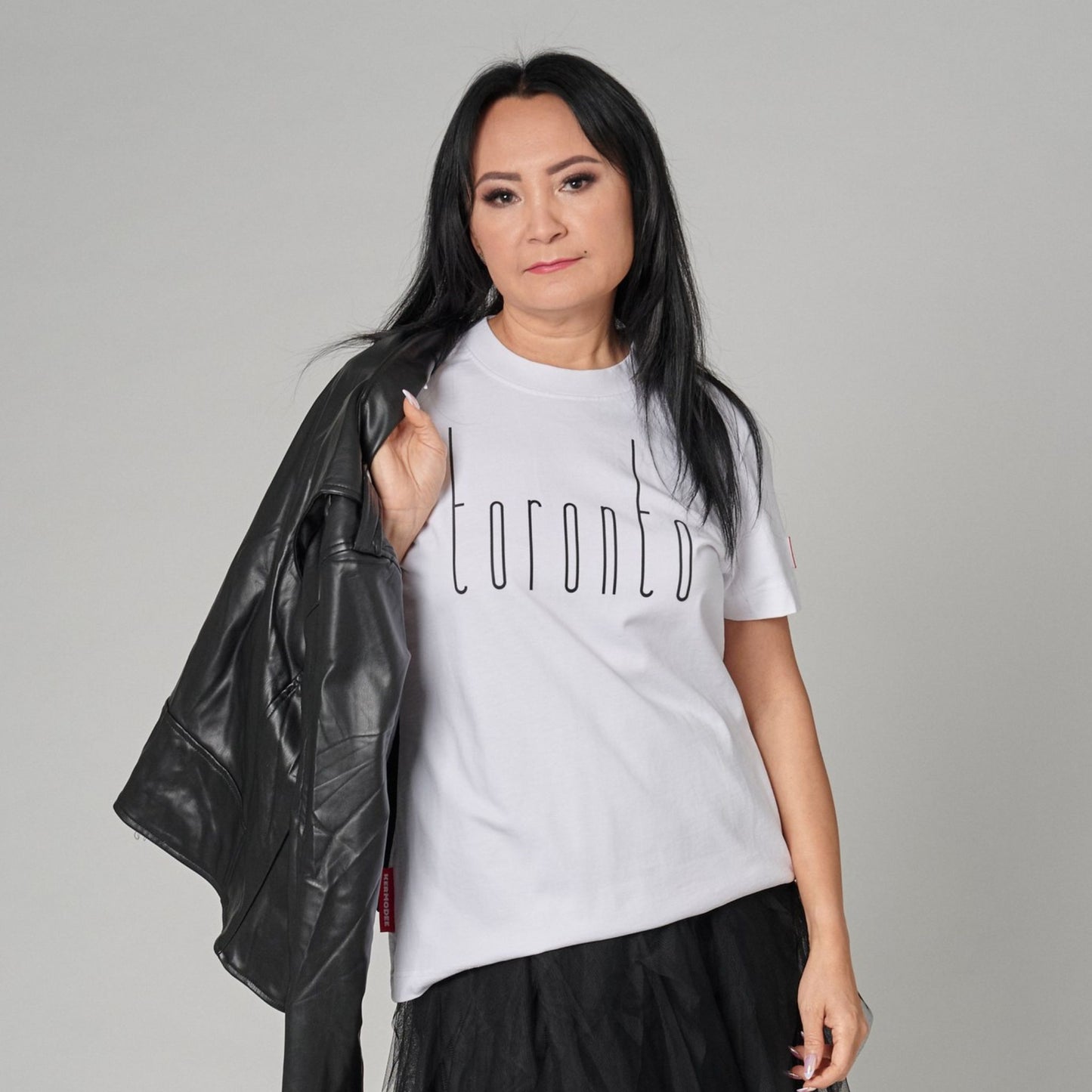 Female model wearing Toronto Ontario Women's T-Shirt with raised high-density Toronto typography layered under a black jacket