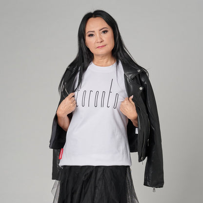 Female model wearing Toronto Ontario Women's T-Shirt featuring raised high-density Toronto city lettering with black jacket styling