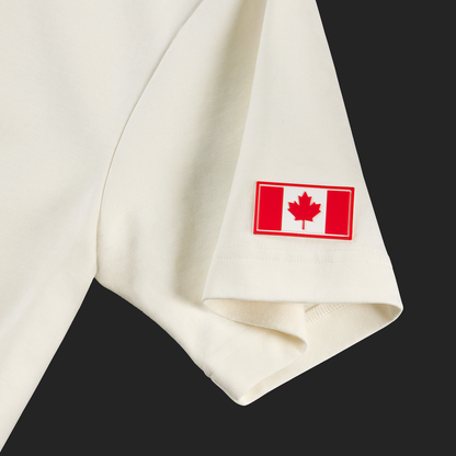 Close-up of Canadian flag patch on left sleeve of off-white t-shirt