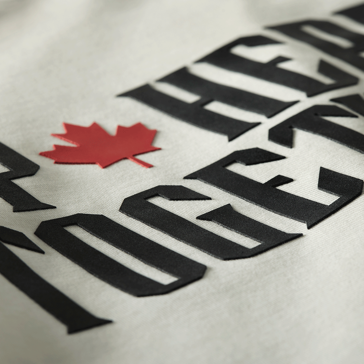 Close-up of raised high-density black lettering and red maple leaf on white Up Here Together t-shirt