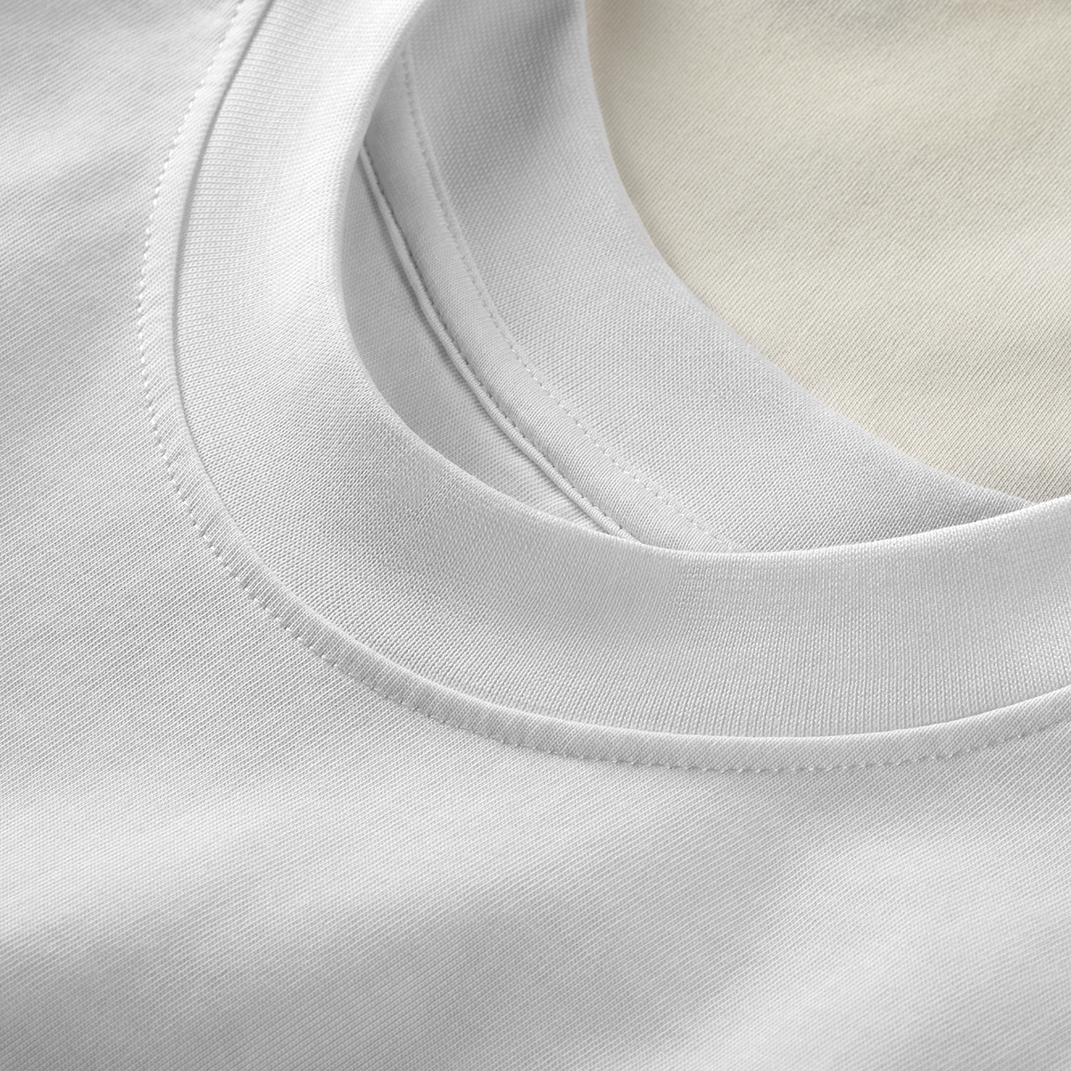 Close-up of ribbed crew neckline with visible stitch on white Kermodee t-shirt